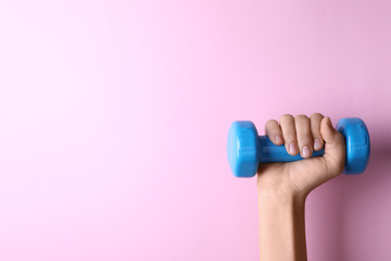 Wall Mural - Woman holding vinyl dumbbell on color background, closeup with space for text