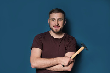 Wall Mural - Young working man with hammer on color background