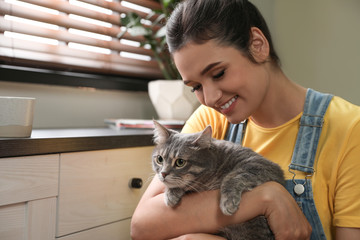 Wall Mural - Young woman with cute cat at home, space for text. Pet and owner