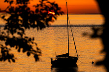 Sailboat Anchored Off An Island During Sunset. Anchored Off Of Lummi Island In The Puget Sound Area Of Northwest Washington State During A Dramatic Sunset In The Salish Sea.