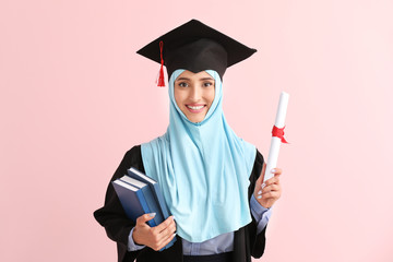 Wall Mural - Muslim female graduate with diploma on color background