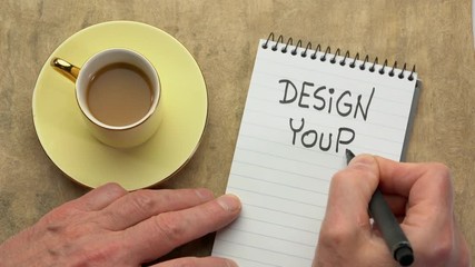 Canvas Print - design your life - a man hand writing a note with a black marker in a spiral notebook, overhead view