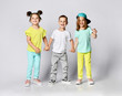 © FAB.1 - Three excited kids in fashion outfits, jumping over the light background. Two sisters and brother, friends in fashionable clothes