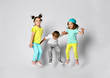 © FAB.1 - Three excited kids in fashion outfits, jumping over the light background. Two sisters and brother, friends in fashionable clothes