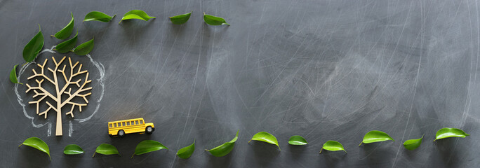 education and back to school concept. Top view photo of school bus next to tree with autumn leaves over classroom blackboard background. top view, flat lay