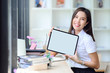 © NAMPIX - Beautiful female student showing tablet with blank screen while sitting at table in library.