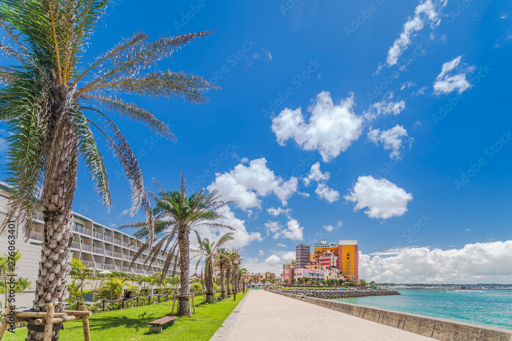 Beach coast lined with palm trees of Distortion Seaside, Oak fashion, Depot Island Seaside buildings and Vessel Hotel Campana in the vicinity of the American Village in Chatan City of Okinawa. - obrazy, fototapety, plakaty 
