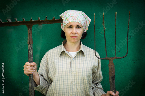 Cuadros en Lienzo Young woman stands with a pitchfork near a stable on a ranch.
