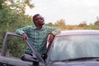 © arrowsmith2 - African man standing on the road near opened door of his car.