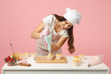 Cute Housewife Chef Cook Confectioner Or Baker In White T-shirt, Toque Chefs Hat Cooking At Table Isolated On Pink Pastel Background In Studio. Cupcake Making Process. Mock Up Copy Space Food Concept.