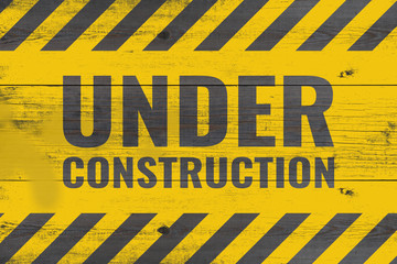 under construction warning message painted on aged wooden planks