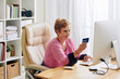 © DragonImages - Smiling senior woman entering information from credit card when paying for online purchases