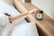 © BoszyArtis - Woman sleep on the bed turns off the alarm clock wake up at the morning, Selective focus.
