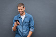 © Rido - Cool smiling man using smartphone on grey wall