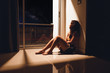 Sad and depressed young woman sitting on the floor in the living room looking outside the doors,sad mood,feel tired, lonely and unhappy concept. Selective focus