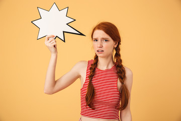 Poster - Confused young beautiful redhead woman posing isolated over yellow background holding speech bubble.