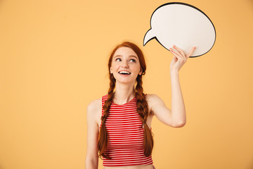 Sticker - Dreaming  young beautiful redhead woman posing isolated over yellow background holding speech bubble.