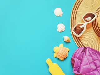 Wall Mural - Yellow sunscreen bottle, sun hat, sunglasses and seashells on a blue background. Flat lay photo beach essentials