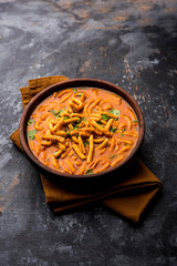 Wall Mural - Dhaba style Sev bhaji/sabzi/curry made in tomato curry with gathiya shev, served in a bowl or karahi, selective focus