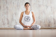 © Rithor - Attractive young woman in cotton suit practices yoga and meditates sitting on a rug on the floor In a spacious bright room