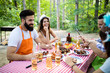 © NDABCREATIVITY - Group of happy friends eating and drinking beers at barbecue dinner