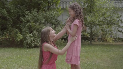 young beautiful woman with long hair sitting on the grass and petting her daughter in the garden. fa