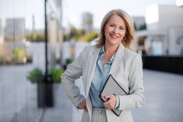 mature business executive professional woman portrait, in suit outside of office in business distric