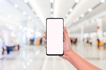 mockup image of hand holding mobile phone with blank white screen with blur office corridor hall way