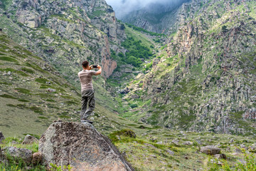 Male hiker takes photo of beautiful mountains in North Caucasus in summer