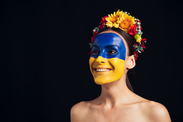 Wall Mural - happy naked young woman in floral wreath with painted Ukrainian flag on skin isolated on black