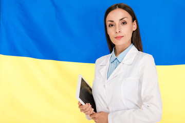 Wall Mural - doctor in white coat holding digital tablet on Ukrainian flag background