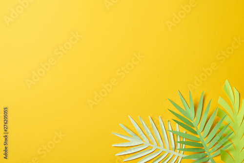 Cuadros en Lienzo top view of paper cut exotic green palm leaves on yellow background with copy sp