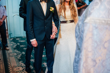 The bride and groom hold hands after the wedding ceremony and leave the church. Happy lovers on a wedding day. close up