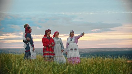 Wall Mural - People in traditional russian folk clothes standing on the field and taking a selfie