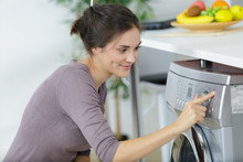 Woman Pressing Button To Start Her Washing Machine