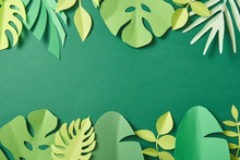 Top View Of Exotic Paper Cut Palm Leaves On Green Background With Copy Space