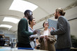 © Seventyfour - Low angle view at multi -ethnic group of business people laughing happily while chatting during coffee break in office, copy space