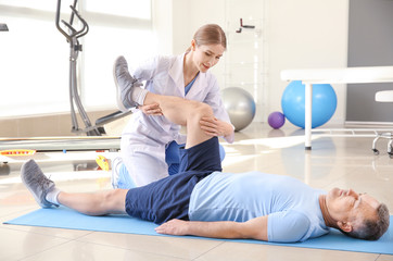 Physiotherapist working with mature patient in rehabilitation center