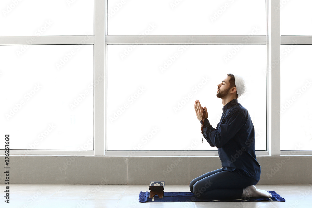 Young Muslim man praying indoors