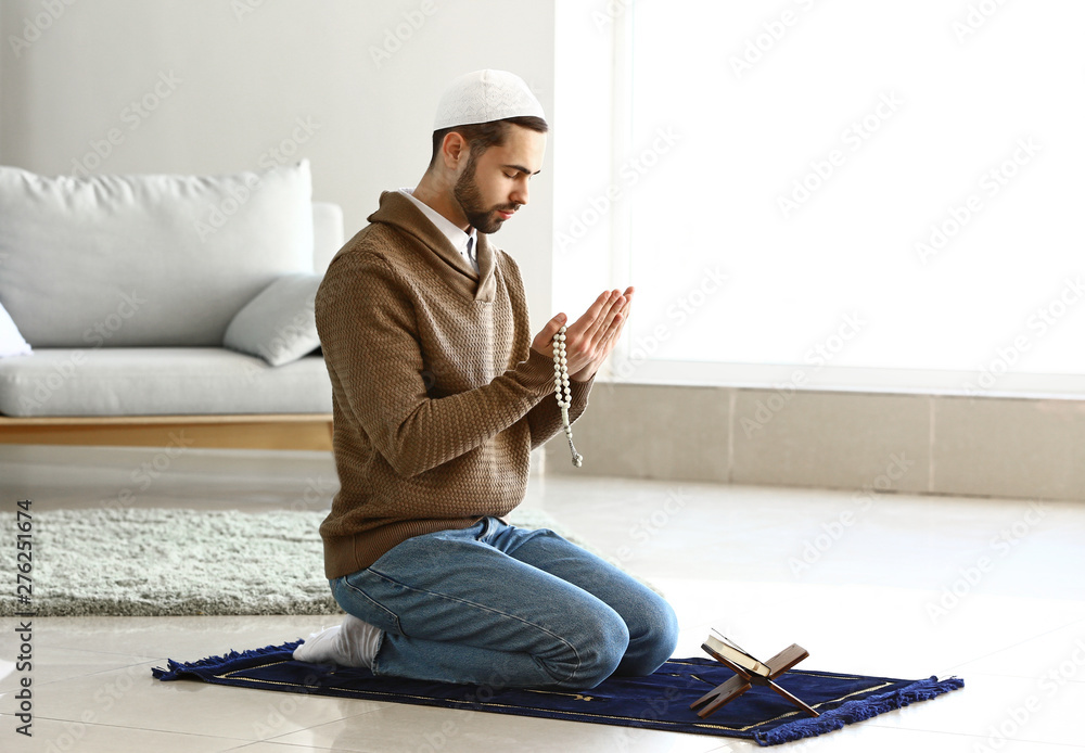 Young Muslim man praying indoors