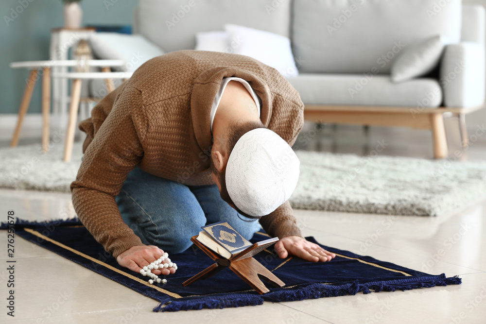 Young Muslim man praying indoors