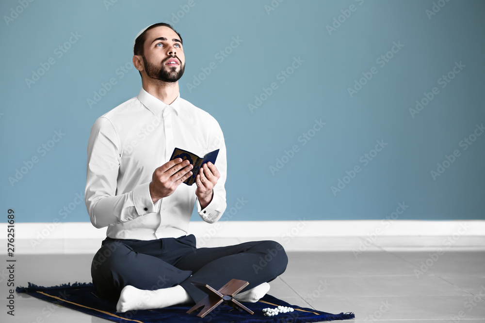 Young Muslim man praying indoors