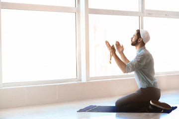 Wall Mural - Young Muslim man praying indoors