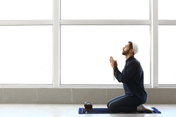 Young Muslim man praying indoors