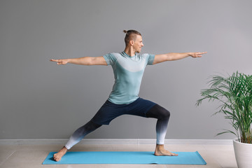 Sporty man practicing yoga in gym