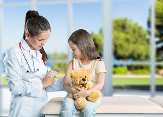 Wall Mural - Young woman doctor with little girl