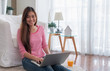 © weedezign - Happy asian woman working on laptop computer at home.female freelancer sitting on carpet on floor work at home in living room..