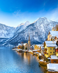 Wall Mural - Classic postcard view of famous Hallstatt lakeside town in the Alps with traditional passenger ship on a beautiful cold sunny day with blue sky and clouds in winter, Austria