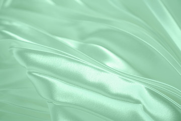 Neo mint color soft satin folded fabric background texture. Close up of ripples on silk fabric. Neo mint color 2020 year concept. Soft cloth background