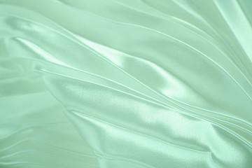 Neo mint color soft satin folded fabric background texture. Close up of ripples on silk fabric. Neo mint color 2020 year concept. Soft cloth background